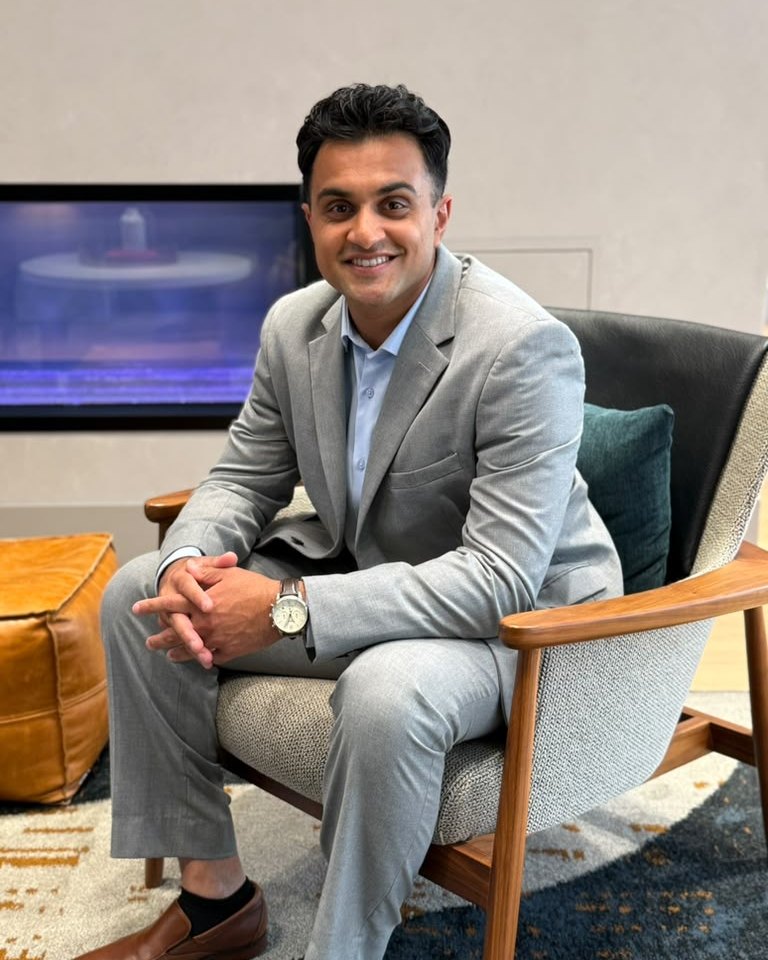 Kiran Aiyar seated in a lounge chair, smiling.